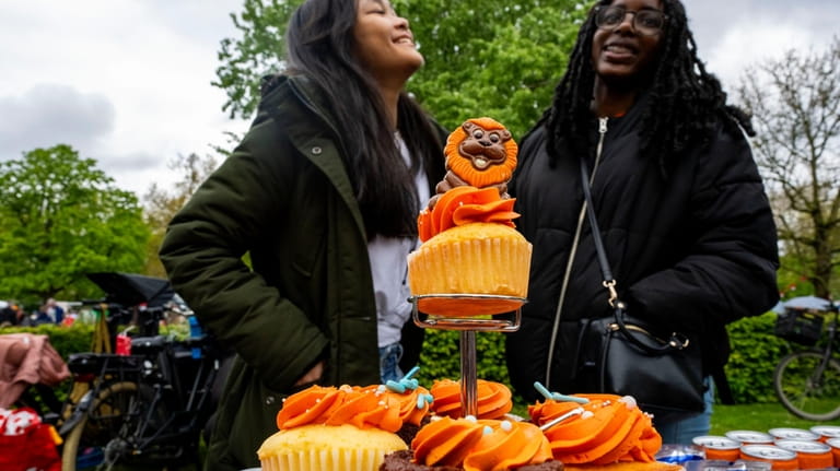 Two girls sell orange pastries during King's Day celebrations in...