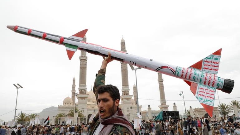 A Houthi supporter raises a mock rocket during a rally...