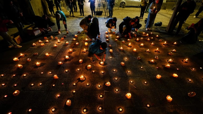 People light candles during a vigil for three police officers,...