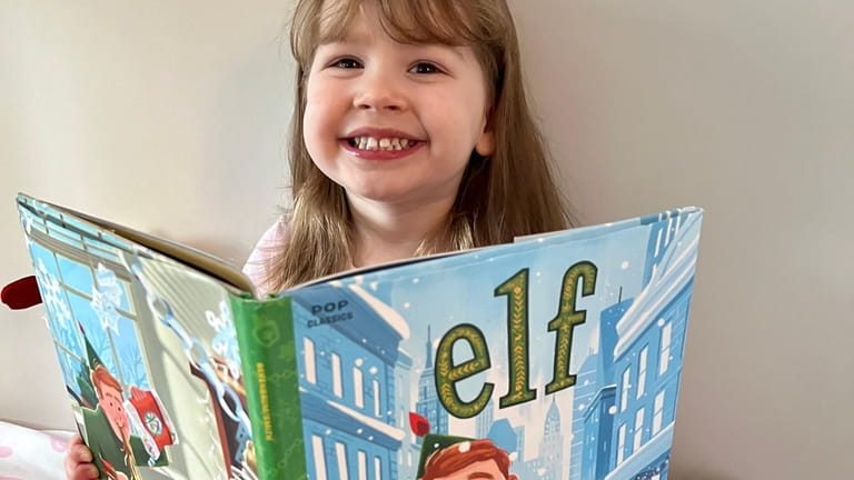 Julianna Ambrosia, 2, has the "Elf" book read to her...
