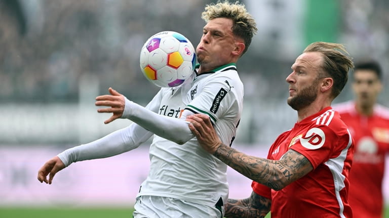 Moenchengladbach's Robin Hack, left, and Berlin's Kevin Vogt, right, challenge...