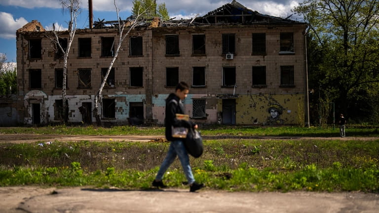 A young man walks past to partially destroyed building in...
