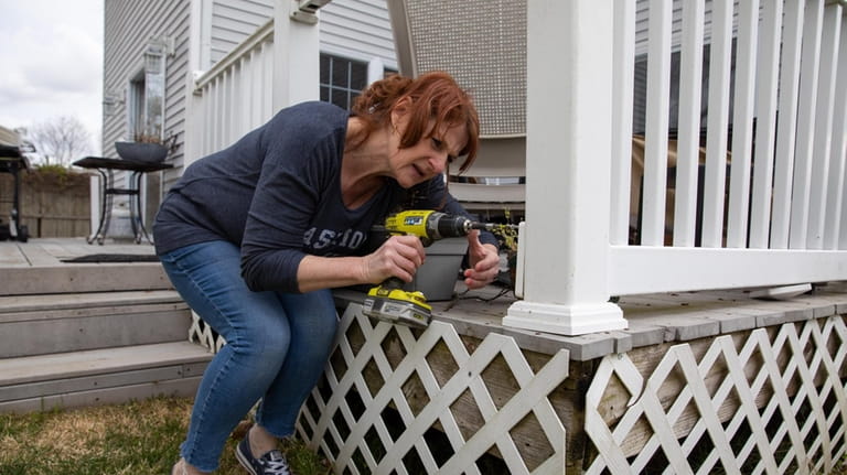 Patricia Cimpric repairs a fence in her backyard in Bayport.