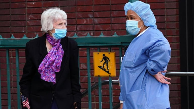 Two women wear masks outside Lenox Hill Hospital in Manhattan during...