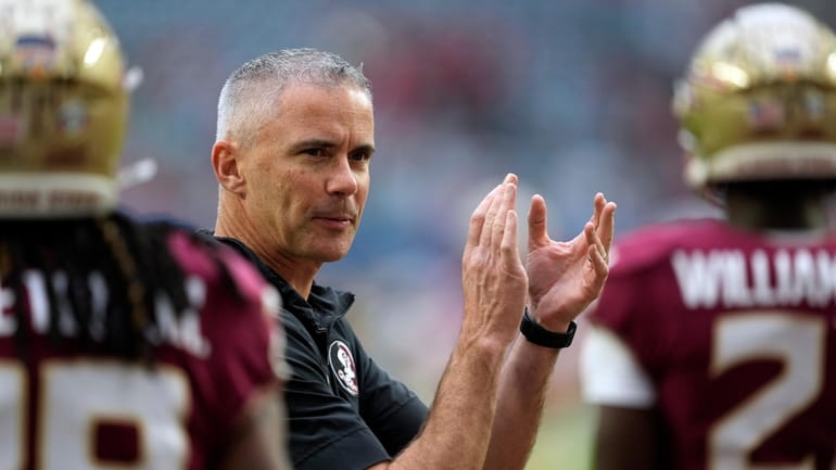 Florida State head coach Mike Norvell claps as his players...