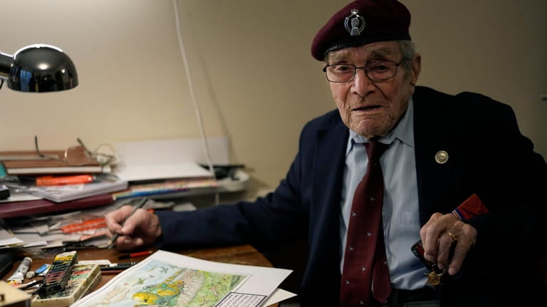 D-Day veteran Bill Gladden shows off one of his paintings,...