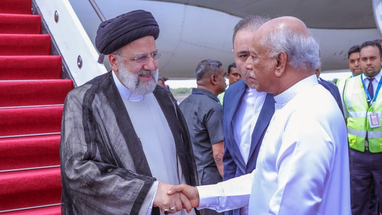Iranian President Ebrahim Raisi, left is received by Sri Lankan...