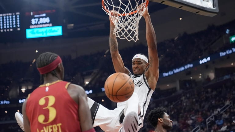 Nets center Nic Claxton (33) hangs from the basket after...