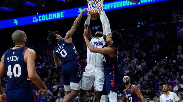 Los Angeles Clippers' Paul George, center, goes up for a...
