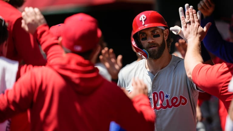 Philadelphia Phillies' Bryce Harper celebrates in the dugout after hitting...