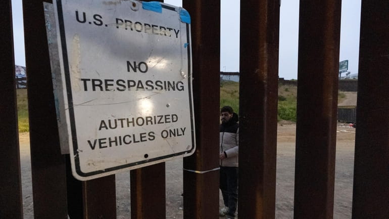 Migrants wait between border walls separating Tijuana, Mexico, and San...