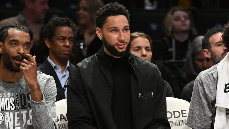 Nets guard Ben Simmons smiles from the bench in the...