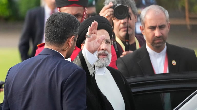 Iranian President Ebrahim Raisi, waves to the media after disembarking...