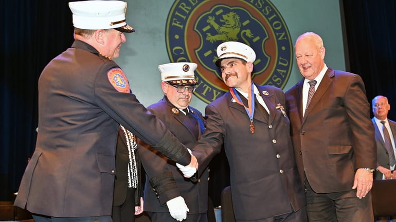 Chief Fire Marshal Michael Uttaro congratulates Lt. Petros Mestheneas after...