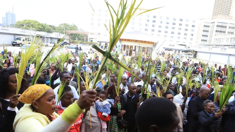 Christian faithful march carrying green Palm branches to commemorate Palm...