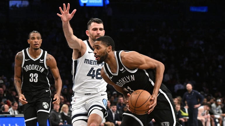 Nets forward Mikal Bridges drives to the basket defended by...