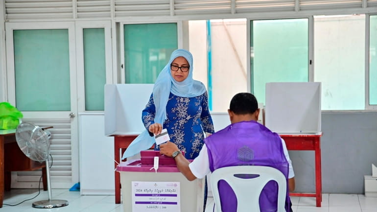 A woman casts her vote at a polling station in...