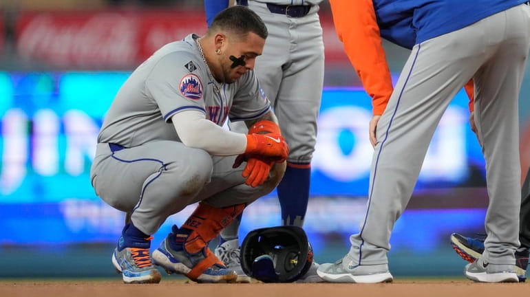 Mets' Francisco Alvarez, left, reacts to an injury on second...