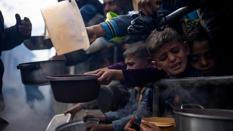 Palestinians line up for a meal in Rafah, Gaza Strip,...
