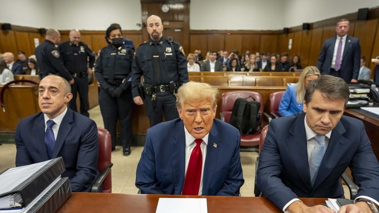 Former President Donald Trump, middle, sits flanked by his attorneys, in...