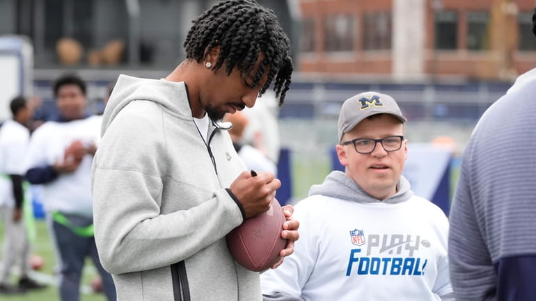 LSU quarterback Jayden Daniels signs a football for a young...