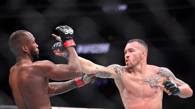 UFC welterweight champion Leon Edwards, left, takes a punch from...