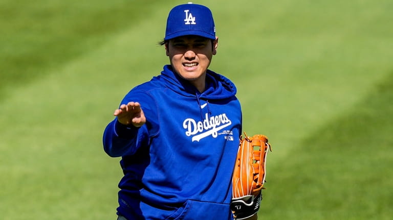Los Angeles Dodgers' Shohei Ohtani reacts as he throws before...