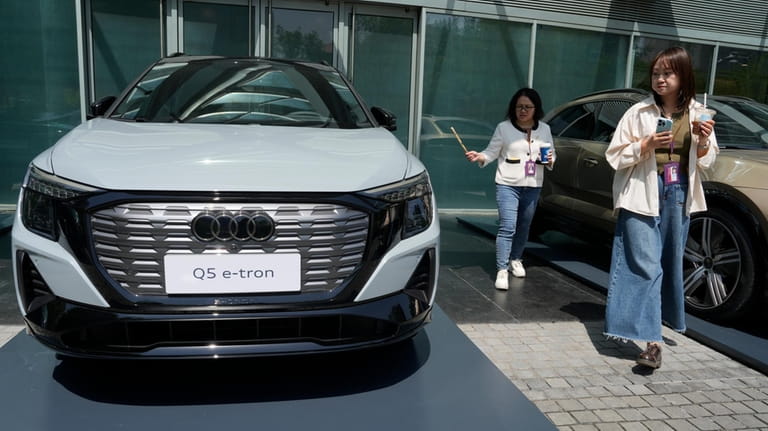 Women look at an Audi Q5 e-tron electric vehicle displayed...