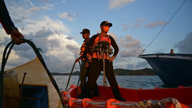 Rescuers stand on a boat during the search for the...