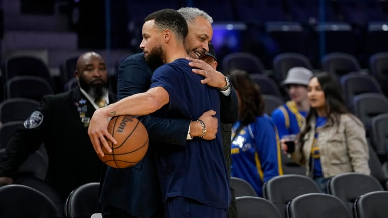Golden State Warriors guard Stephen Curry, right, is hugged by...