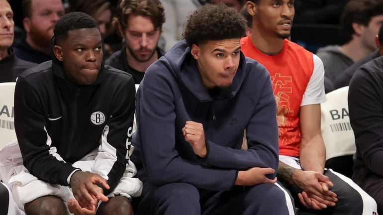 Nets guard Dennis Schroder, left, and Cam Johnson sit on the...
