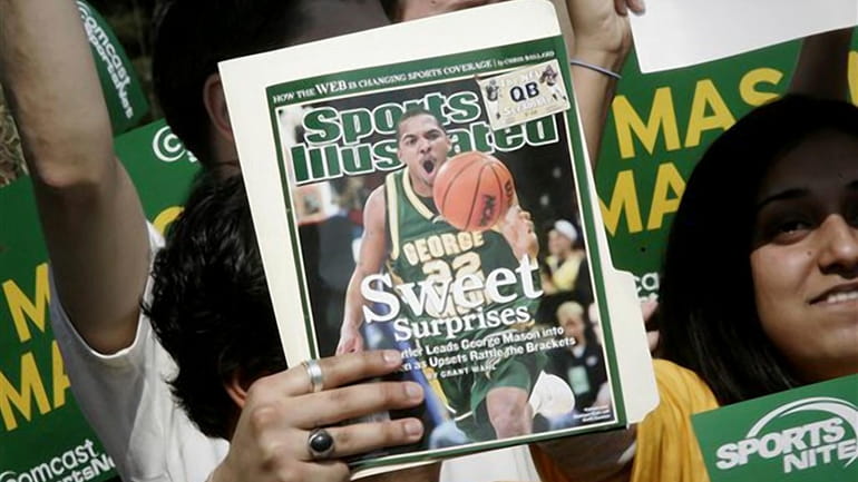 A George Mason University fan holds up the cover of...