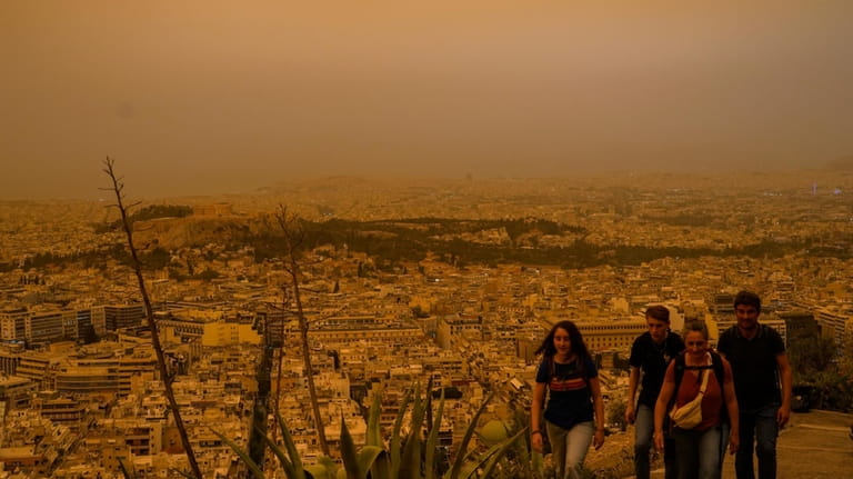 Tourists walk at the Lycabettus hill as the city of...