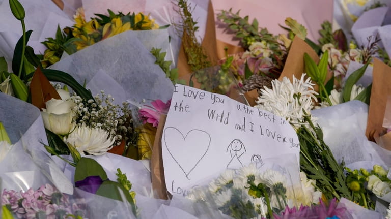 A note is attached to flowers at a tribute near...