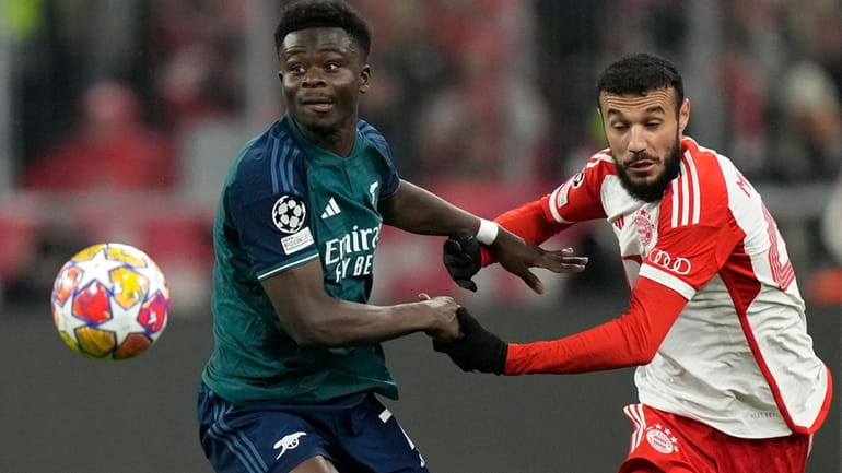 Bayern's Noussair Mazraoui, right, challenges Arsenal's Bukayo Saka during the...