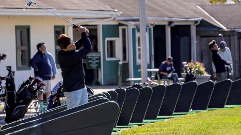 Golfers practice at the driving range at Eisenhower Park in...