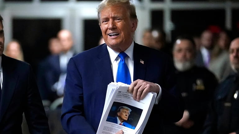 Former President Donald Trump holds up news clippings as he...