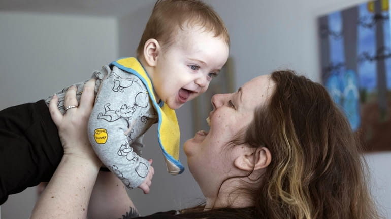 Nicole Slemp, a new mother of seven-month-old William, lifts up...