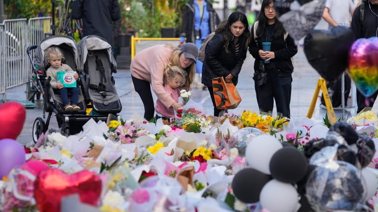 People lay flowers at a tribute for the victims in...