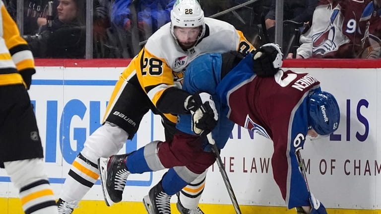 Pittsburgh Penguins defenseman Marcus Pettersson, left, knocks over Colorado Avalanche...