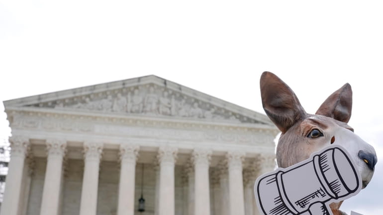 A demonstrator stands outside the Supreme Court as the justices...