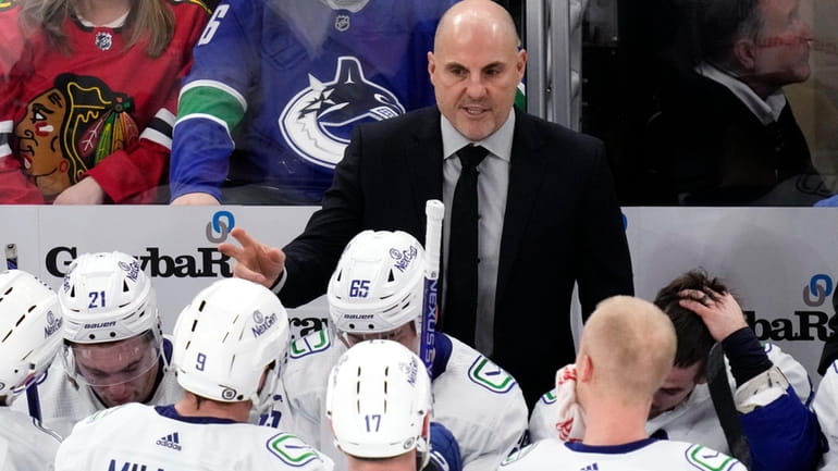 Vancouver Canucks head coach Rick Tocchet, top, talks to players...