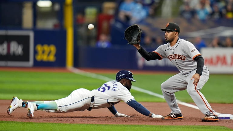 Tampa Bay Rays' Randy Arozarena, left, dives back to first...