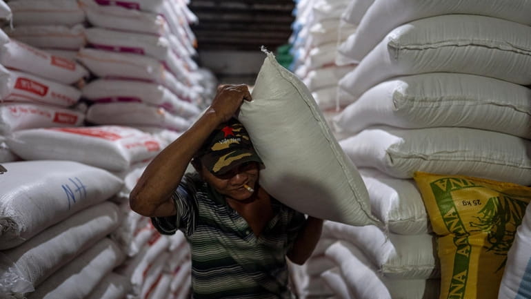 A worker carries a bag of rice at a warehouse...