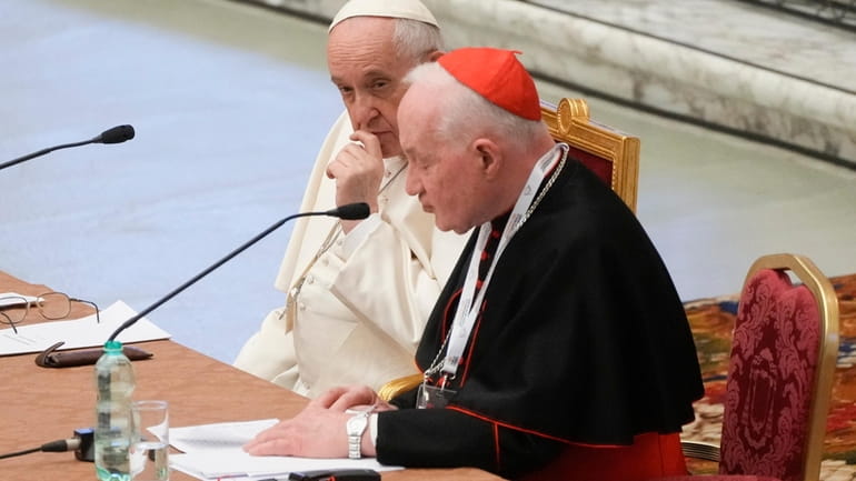 Pope Francis, left, listens to Cardinal Marc Ouellet's opening address...