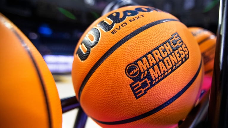 A basketball with a March Madness logo rests on a...