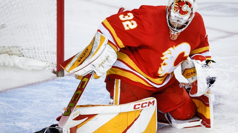 Calgary Flames goalie Dustin Wolf (32) kicks away a shot...