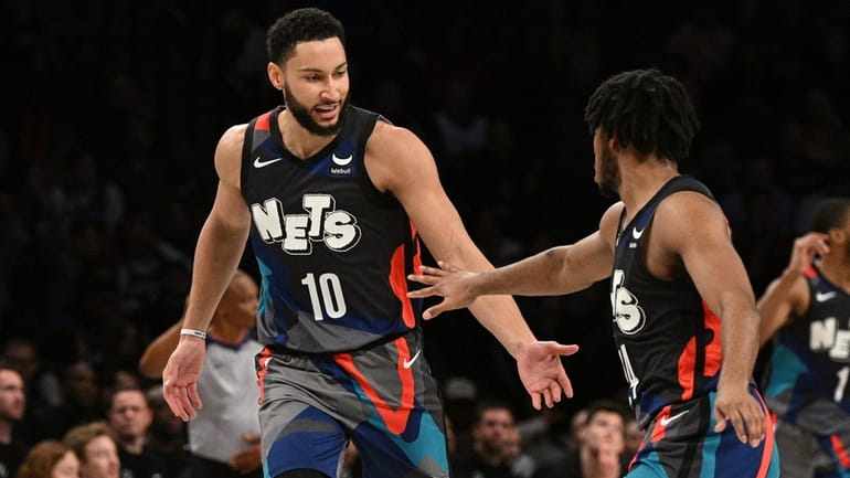 Nets guard Ben Simmons slaps five with guard Cam Thomas...