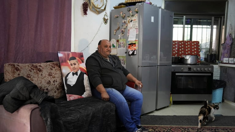 Ali Halhouli sits next to a photo of his slain...