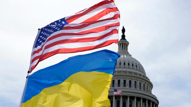 The American and Ukrainian flags wave in the wind outside...